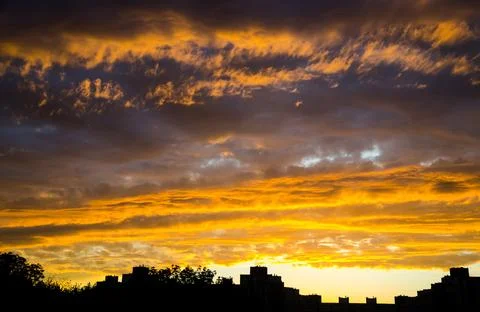 Dramatic golden sunset clouds over city skyline 写真素材