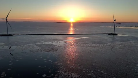 Dramatic golden sunset over frozen sea with offshore wind turbines Stock Footage 335263682