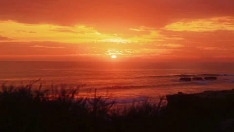 Dramatic Golden Sunset Over Ocean Horizon with Coastal Cliff Silhouette Stock Footage 332089225