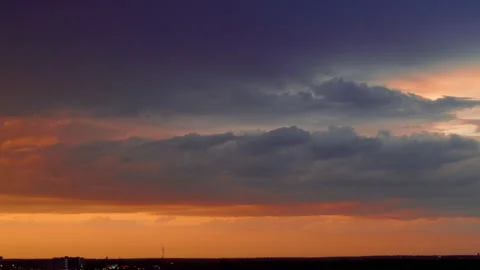 Dramatic golden sunset over suburban town skyline with heavy clouds and glowing Stock Footage 335960273