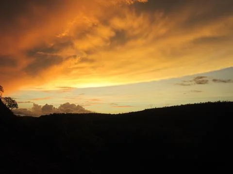 Dramatic Golden Sunset Sky Over Silhouette Hills Stock Photos