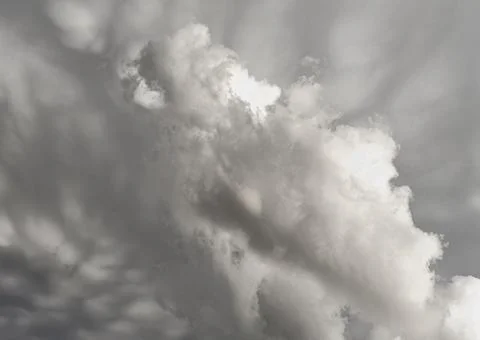 Dramatic grayscale cloudscape with towering cumulus formations casting soft Stock Photos