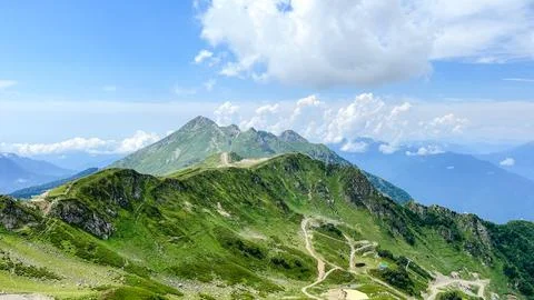 Dramatic green mountain peak with alpine trails and blue sky Stock Photos