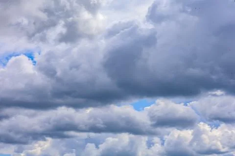 Dramatic grey clouds fill the sky with patches of bright blue peeking through Stock Photos