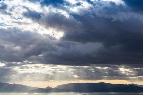 Dramatic heavy clouds above the landscape with sunrays coming through. Stock Photos