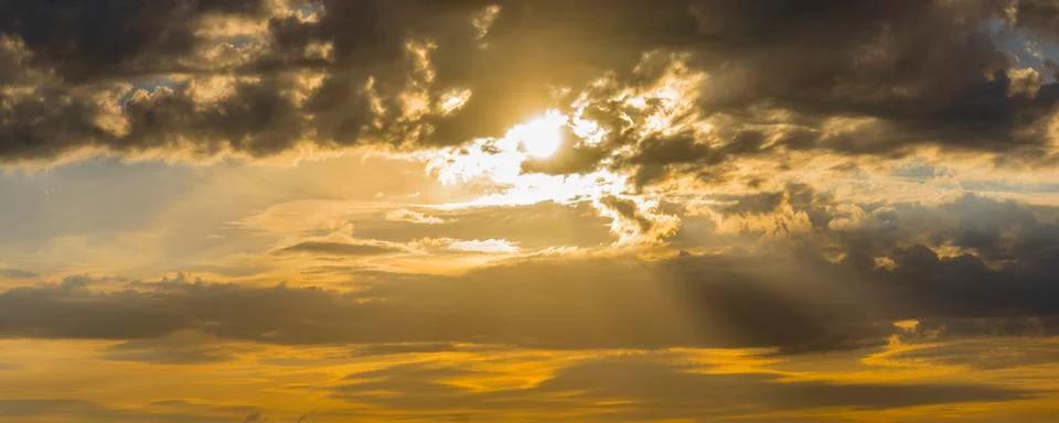 Dramatic impressive background - sky with bright sun and dark clouds Stock Photos