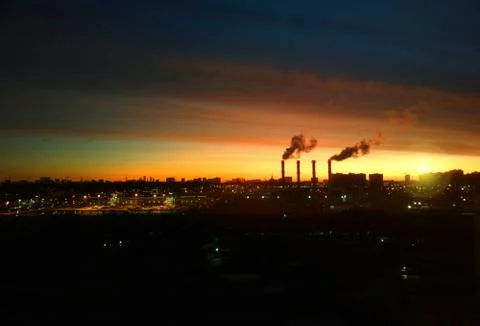 Dramatic industrial chimneys during sunset background Stock Photos