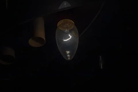 A dramatic interior scene with glowing lightbulbs hanging from the dark Фото