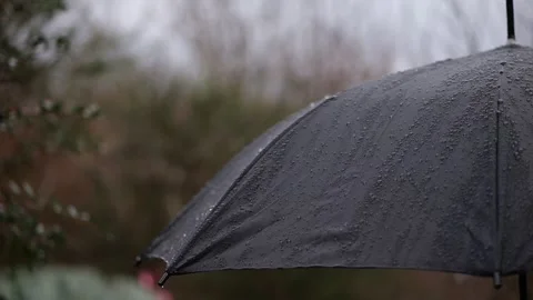 The dramatic interplay of rain on a black umbrella, slow-motion droplets bu.. Video stock 264818671