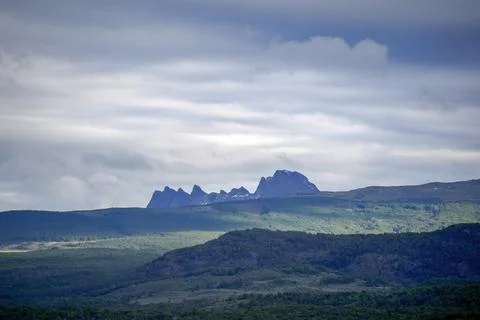 Dramatic Jagged Mountain Peaks Over Green Patagonian Landscape Stock Photos