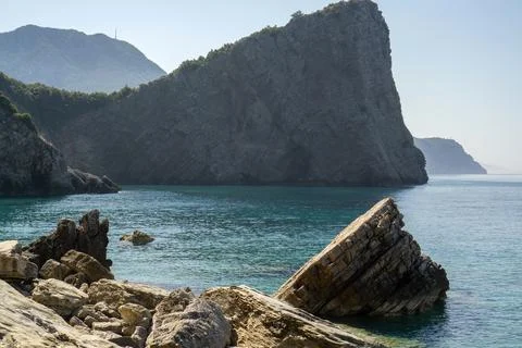 Dramatic jagged rock formation sticking out of clear turquoise water along .. Stock Photos