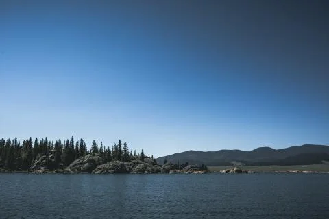 Dramatic lake and forest with mountain range under cloudy sky Stock Photos
