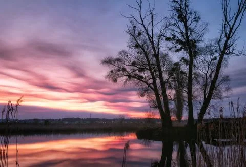 Dramatic landscape with beautiful glowing sky with clouds over a lake at suns Stock Photos