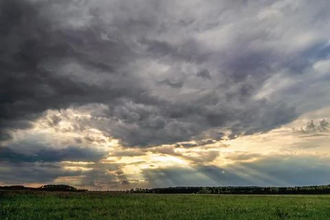 Dramatic landscape with dark storm clouds and sun rays Stock Photos