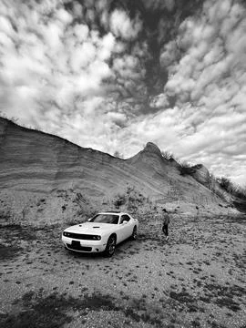 Dramatic landscape with a modern car under a cloudy sky Stock Photos