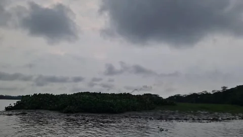 Dramatic landscape of river island with brick kiln smoke under cloudy sky Video stock 332503462