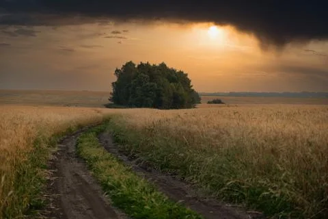 Dramatic landscape view with heavy black stormy clouds over a road snaking. Stock Photos