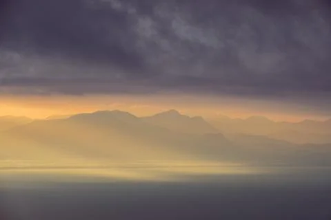 Dramatic landscape view of sunrise over mountains and the ocean Stock Photos