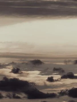 Dramatic layered clouds in warm sepia tones with soft light breaking throug.. 写真素材