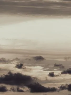 Dramatic layered clouds in warm sepia tones with soft light breaking throug.. Stock Photos
