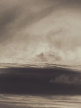 Dramatic layered clouds in warm sepia tones with soft light breaking throug.. Stock Photos