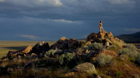 Dramatic light and woman on rocks in deseert sunset, saturated, 4k Stock Footage 274686267