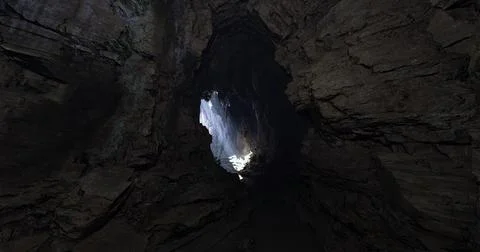 Dramatic light breaking through a cave opening at dusk in a secluded location Stock Illustration