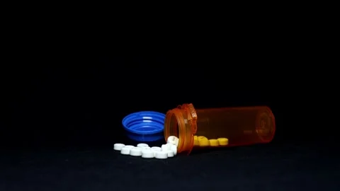 Dramatic Light Circling Spilled White Pills Next to Pill Bottle Video stock 249354857