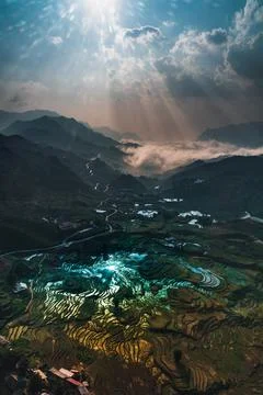 Dramatic light effects on a sunrise shot of rice fields in a valley surrounde Stock Photos