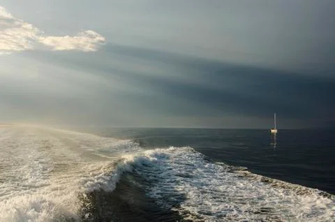 Dramatic Light over the Sea with Waves and Sailboat Stock Photos