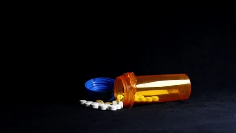 Dramatic light over White Pills Spilled Out of Bottle on Black Background  Video stock 249356159