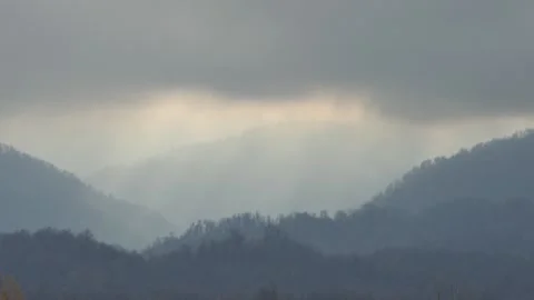 Dramatic light piercing clouds above forested mountain ridges Stock Footage 318684637