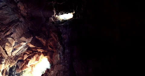 Dramatic light shines through rocky formations in deep cave Stock Footage 310453006