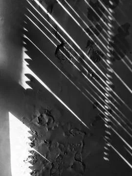 Dramatic light streaks across textured peeling wall creating abstract shadow Stock Photos