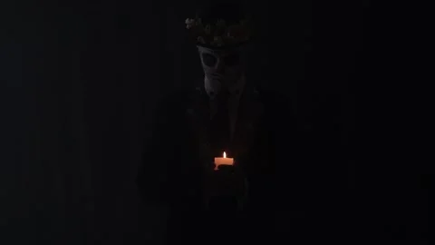 Dramatic lighting, a man with the makeup of a skull is holding a candle, 4k Stock Footage 138426038
