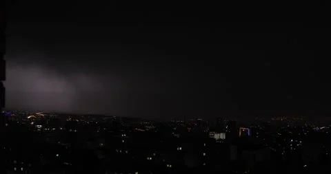 Dramatic Lightning bolt slicing across night sky above illuminated city skyline Stock Footage 317812151