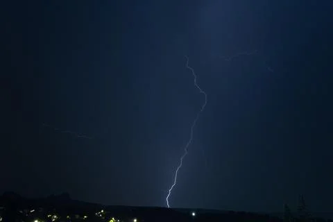 Dramatic lightning bolt striking from a dark storm cloud at night Photos