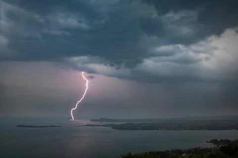 Dramatic lightning bolt striking Lake Garda, Italy at dusk Stock Photos