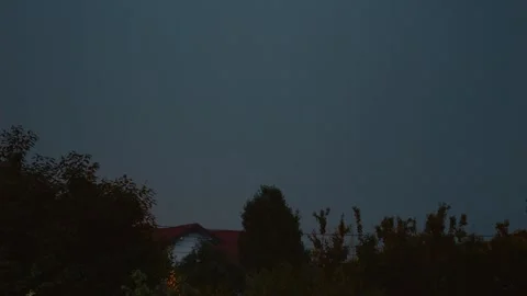 Dramatic lightning illuminates the blue sky over a village during a storm Stock Footage 318821196
