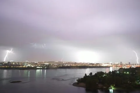 Dramatic lightning storm lights up the city skyline over the river at night Stock Photos
