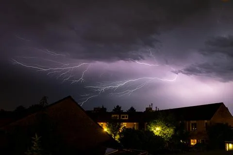 Dramatic lightning storm over suburban houses illuminating the night sky 库存照片