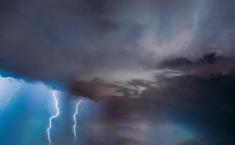 Dramatic lightning strike during severe thunderstorm with dark clouds over Stock Photos