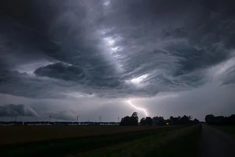 Dramatic lightning strike under dark supercell storm clouds over rural farmland Foto stock