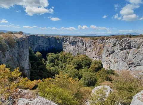 Dramatic limestone canyon surrounded by green forest and mountains. Stock Photos