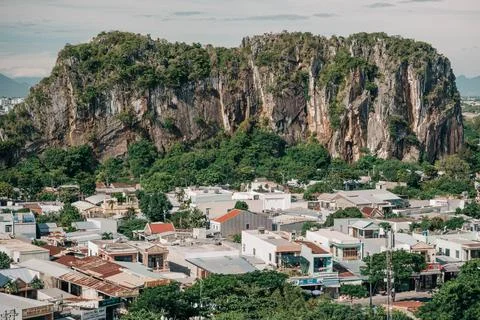 Dramatic limestone karst mountain rising above a dense urban neighborhood in Da Stock Photos
