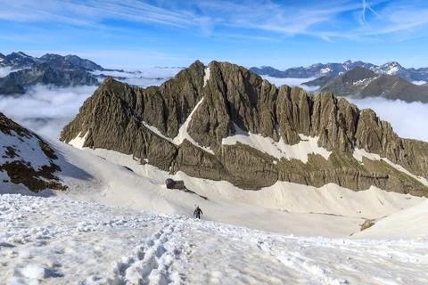 Dramatic Limestone Ridge Rising Above Summer Snow in the Pyrenees 스톡 사진