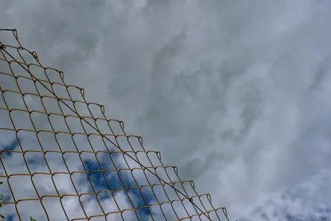 Dramatic lined cloudscape with separation by metallic net. Conceptual, abstra Stock Photos