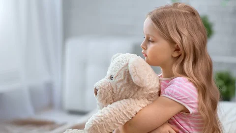Dramatic lonely kid embrace toy bear feeling sadness at cosiness home. Shot with Stock Footage 127678252