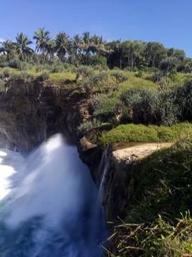 Dramatic long exposure of a seaside waterfall plunging off a rocky cliff. Stock Photos