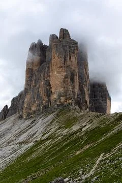Dramatic looking mountain peak rising into the clouds on green rocky hills Stock Photos